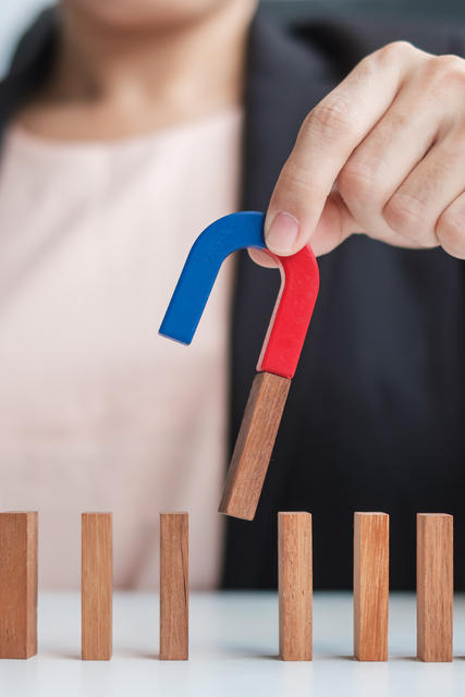 human resources business hand holding magnet and pulling man